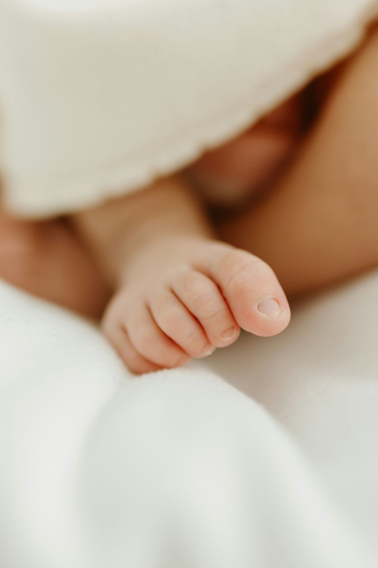 a close up of a baby's hand on a bed